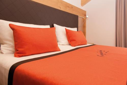 a bed with orange and white pillows on it at Sport Garni Kapplerhof – Ischgl/Kappl in Kappl
