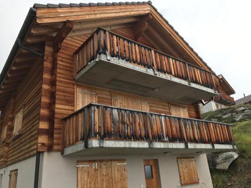 a house with wooden doors and a balcony at Farfalla in Blatten bei Naters