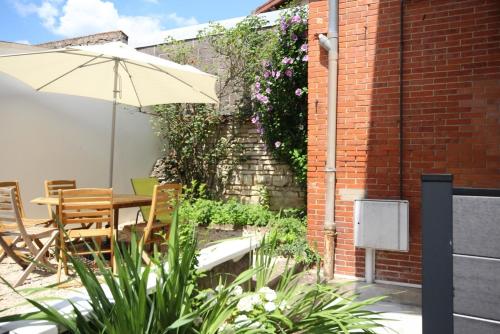 a patio with an umbrella and a table and chairs at Appartements Le Cru Colbert in Beaune