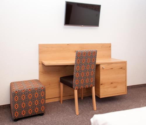 a desk with a chair and a tv on a wall at Sport Garni Kapplerhof – Ischgl/Kappl in Kappl