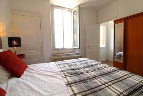 a bedroom with a large bed with a red pillow at Appartements Le Cru Colbert in Beaune