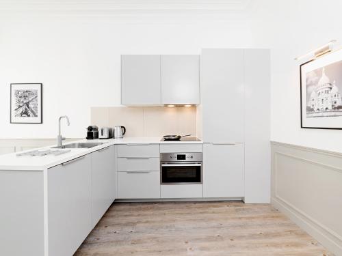 Il comprend une cuisine blanche avec des placards blancs et du parquet. dans l'établissement LivinParis - Luxury 4 Bedrooms Opera I, à Paris