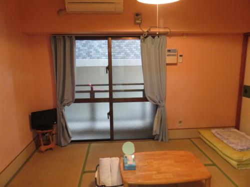 Habitación con ventana, mesa y cama. en Hostel Hakuseiso, en Naha