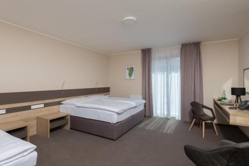 a hotel room with two beds and a desk at Hotel Panská Zahrada in Dobřichovice