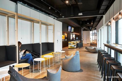 una donna seduta su un divano in una stanza con sedie di Sleep Well Youth Hostel a Bruxelles