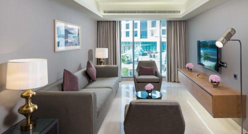 a living room with a couch and a tv at Grand Millennium Muscat in Muscat