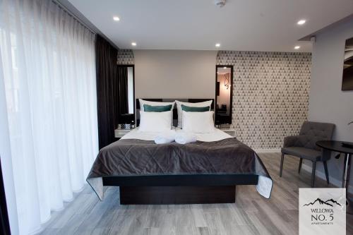 a bedroom with a large bed and a chair at Willowa NO. 5 APARTAMENTS in Wisła