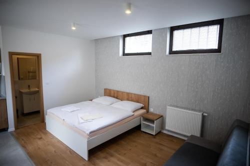 a bedroom with a white bed and two windows at Ubytovanie Alej Bojnice in Bojnice