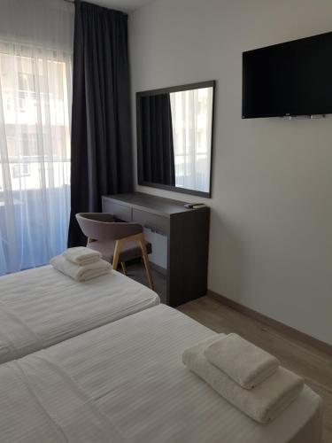 een slaapkamer met 2 bedden, een bureau en een televisie bij Les Palmiers Petrou Apartments in Larnaka