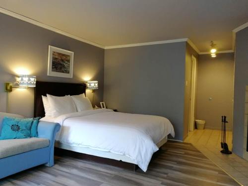 a bedroom with a large white bed and a couch at Motel Chantolac in Sainte-Adèle
