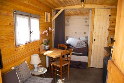 a small room with a table and a bed at La Maison du Bonheur Roulotte in Saint-Ouen-sous-Bailly