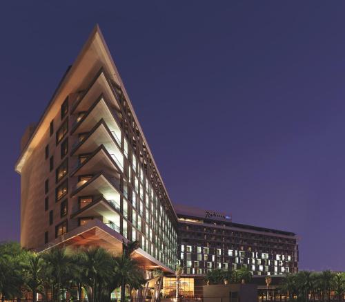 a tall building with palm trees in front of it at Radisson Blu Hotel, Abu Dhabi Yas Island in Abu Dhabi