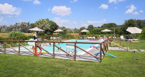 a pool with people playing in it and a woman standing in the grass at Tenuta San Giovanni Lucca in Lucca