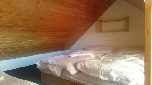 an unmade bed in a room with a wooden wall at Pension Harcovna in Frýdlant nad Ostravicí