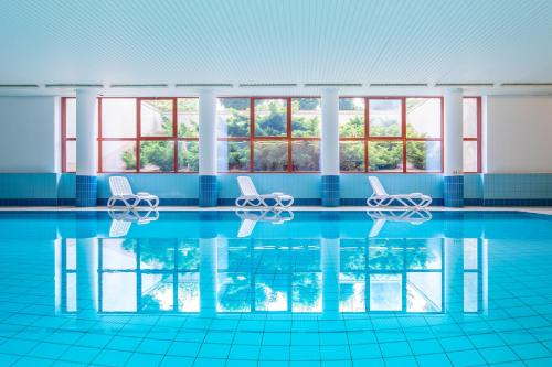 a swimming pool with chairs in the water at Mercure Jelenia Góra in Jelenia Góra
