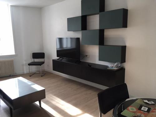 a living room with a flat screen tv on a wall at Appartements Le Cru Colbert in Beaune