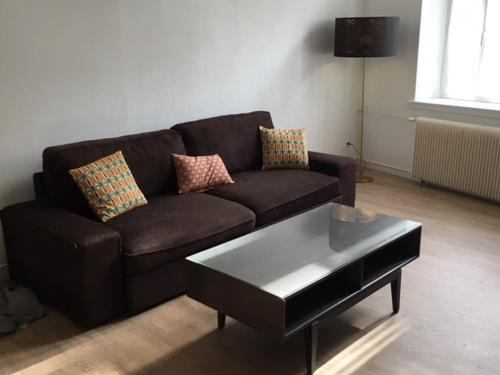 a living room with a brown couch and a coffee table at Appartements Le Cru Colbert in Beaune