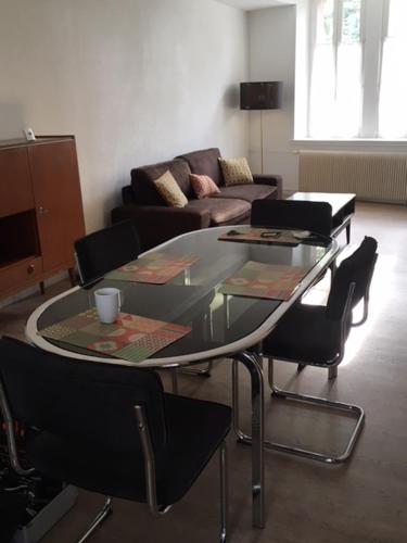 a living room with a glass table and chairs at Appartements Le Cru Colbert in Beaune