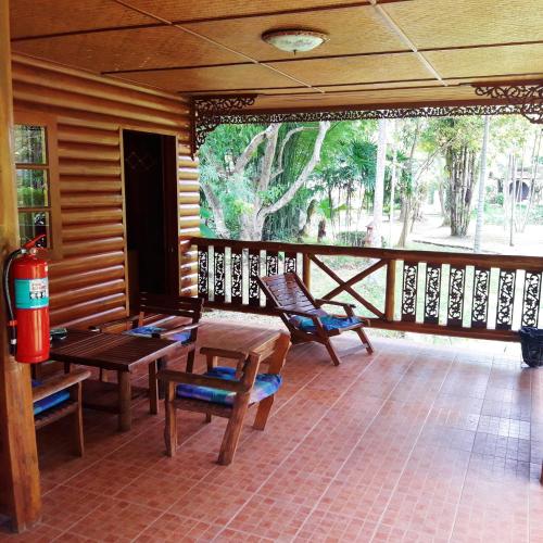 a porch with wooden tables and chairs and a large window at Huan Chiang Dao Resort in Chiang Dao