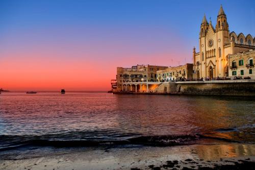 a building next to the water at sunset at Modern 2BR Sliema Apartment in Sliema