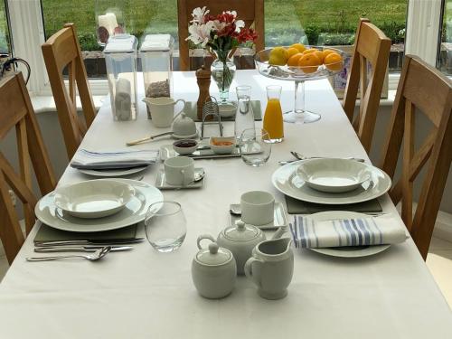 una mesa blanca con platos y vasos. en Hysett House, en Midhurst