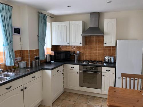 a kitchen with white cabinets and a stove top oven at Jubilee House in Oakham