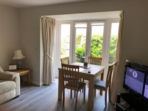 a living room with a dining room table and a television at Jubilee House in Oakham