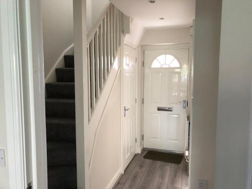 a white hallway with a white door and stairs at Jubilee House in Oakham
