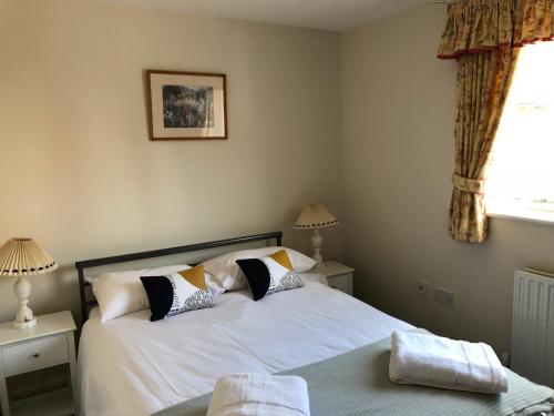 um quarto com uma cama com lençóis brancos e almofadas em Jubilee House em Oakham