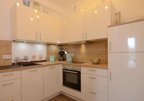a white kitchen with white cabinets and a refrigerator at Appartment Ferienwohnung mit großer Terrasse Ohlerich Speicher Wismar in Wismar