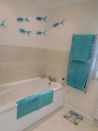 a bathroom with a tub and blue fish on the wall at Hysett House in Cocking
