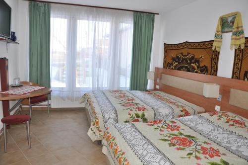 a bedroom with two beds and a table and a window at Pensiune Muzeu Traditional Poveste in Transilvania in Sighişoara