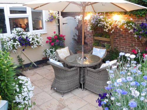 a patio with a table and chairs and flowers at Hysett House in Cocking