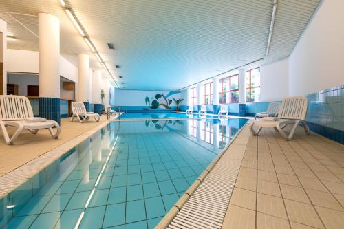 a swimming pool in a building with chairs around it at Mercure Jelenia Góra in Jelenia Góra