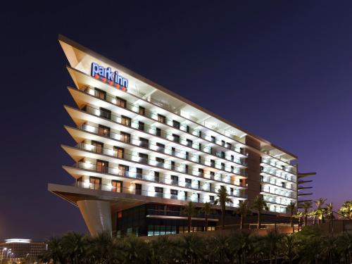 a hotel building with a lit up facade at night at Park Inn by Radisson Abu Dhabi Yas Island in Abu Dhabi