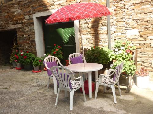 a table with four chairs and an umbrella at Pensión Santa Rosa in Samos