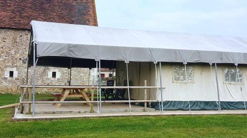 a tent with a picnic table in front of a building at Camping Parc de la Brenne in Lignac