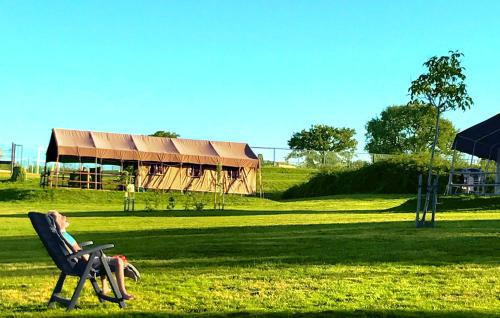 a woman sitting in a chair in a field at Camping Parc de la Brenne in Lignac