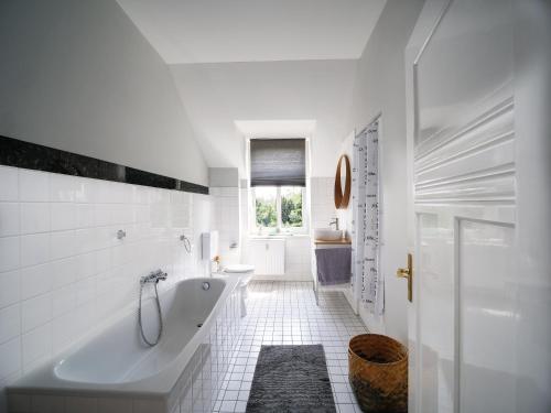 Baño blanco con bañera y lavamanos en City Apartments Siegburg, en Siegburg