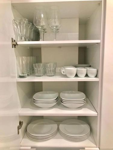 a white shelf with plates and bowls and wine glasses at Lujoso duplex en la playa con vistas al mar in Torremolinos