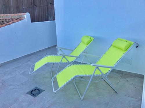 two chairs with green cushions sitting next to a table at Lujoso duplex en la playa con vistas al mar in Torremolinos
