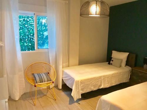 a bedroom with a bed and a chair and a window at Lujoso duplex en la playa con vistas al mar in Torremolinos