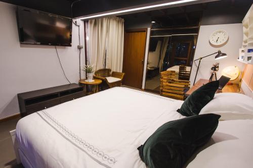 a bedroom with a large white bed and a tv at Narra House Sukhumvit58 in Bangkok