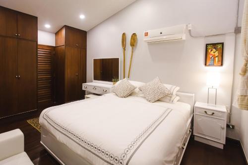 a bedroom with a white bed and a television at Narra House Sukhumvit58 in Bangkok