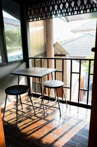 two tables and two stools sitting on a balcony at Narra House Sukhumvit58 in Bangkok