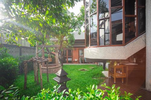 a garden with a house with a tree at Narra House Sukhumvit58 in Bangkok