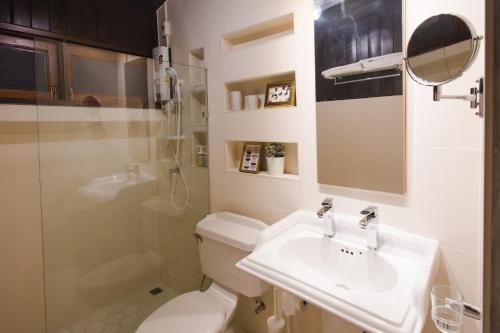 a white bathroom with a toilet and a sink at Narra House Sukhumvit58 in Bangkok