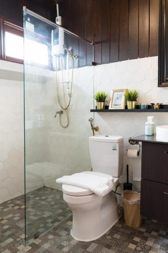 a bathroom with a toilet and a glass shower at Narra House Sukhumvit58 in Bangkok