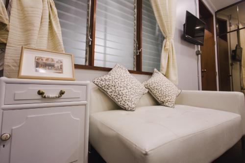 a white couch sitting in a room with a window at Narra House Sukhumvit58 in Bangkok