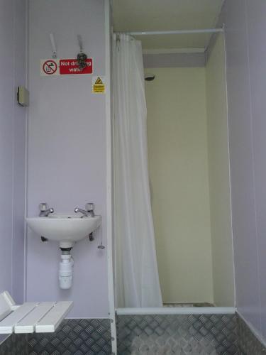 a bathroom with a sink and a shower curtain at The Valley Bell Tents, Bring Your Own Bedding in Amroth